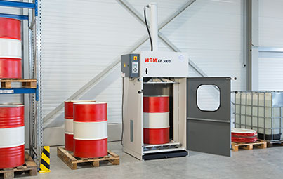 Fasspresse HSM FP 3000 inmitten Arbeitsumgebung mit stehenden rot-weißen Fässern und Pressgut