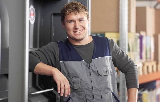 Mann lehnt an Ballenpresse und lächelt